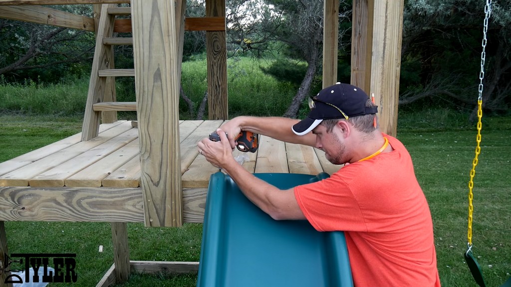 screwing wavy slide into place on diy swing set