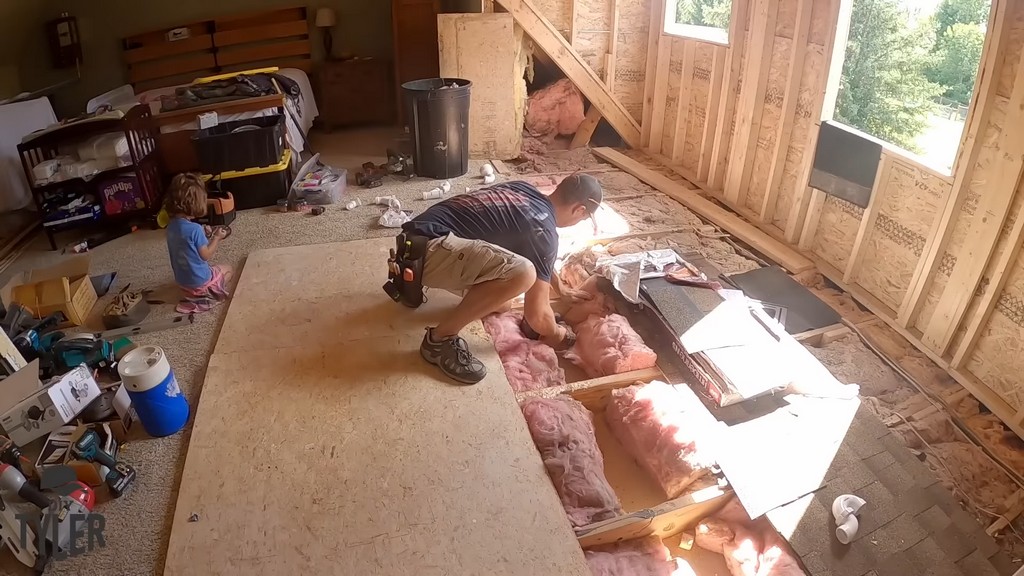 man drilling holes for plumbing beneath floorboards