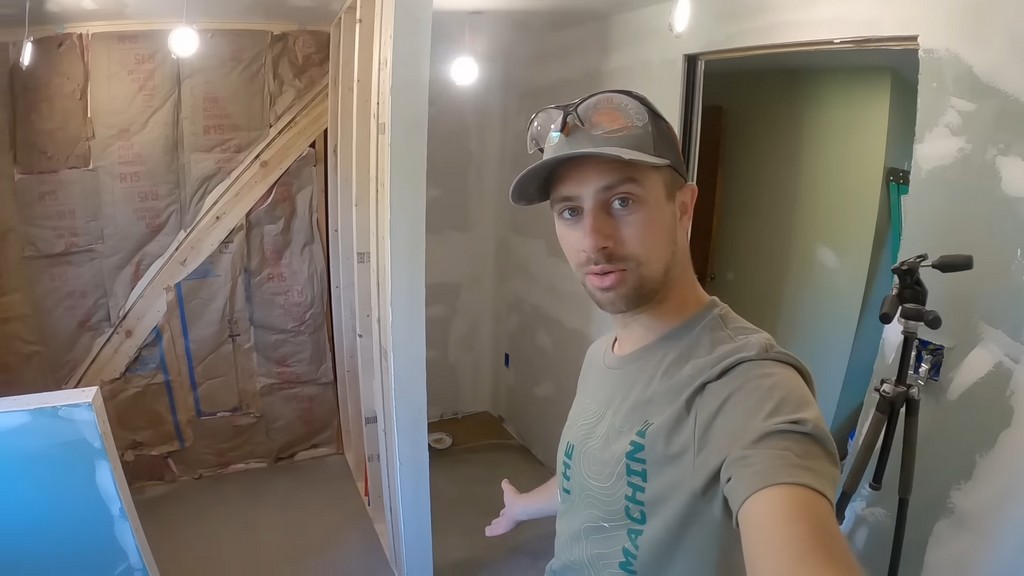 man standing in front of set self-leveling compound in unfinished bathroom