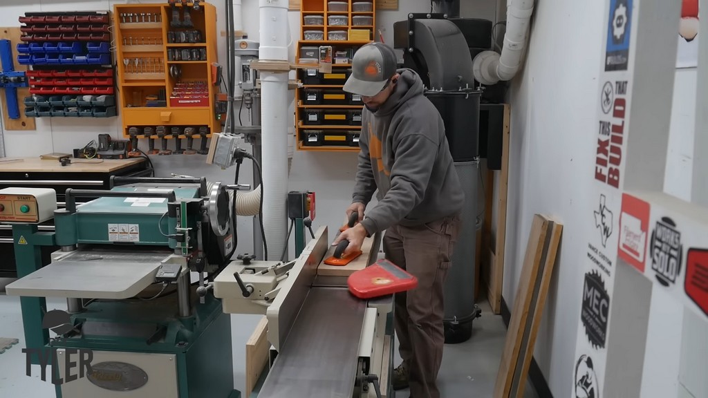 man running ash wood board through jointer machine