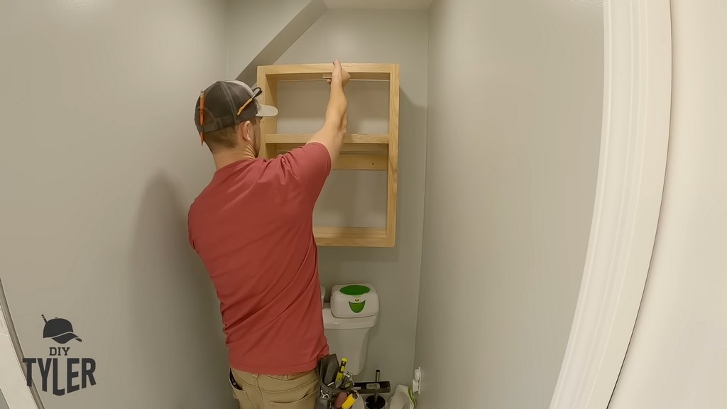 man installing DIY functional bathroom shelf