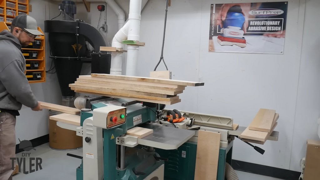 man running ash wood board through planer machine