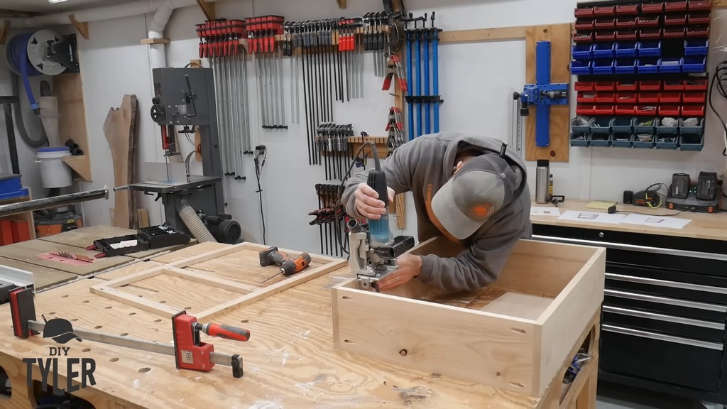 man cutting biscuit joints into box frame for DIY functional bathroom shelf