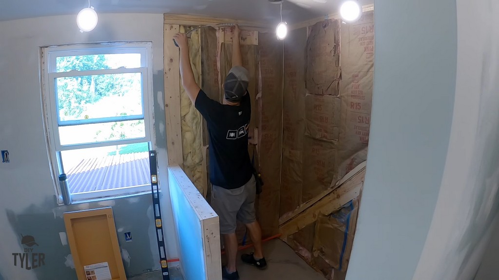 man measuring walk-in shower wall for Kerdi board