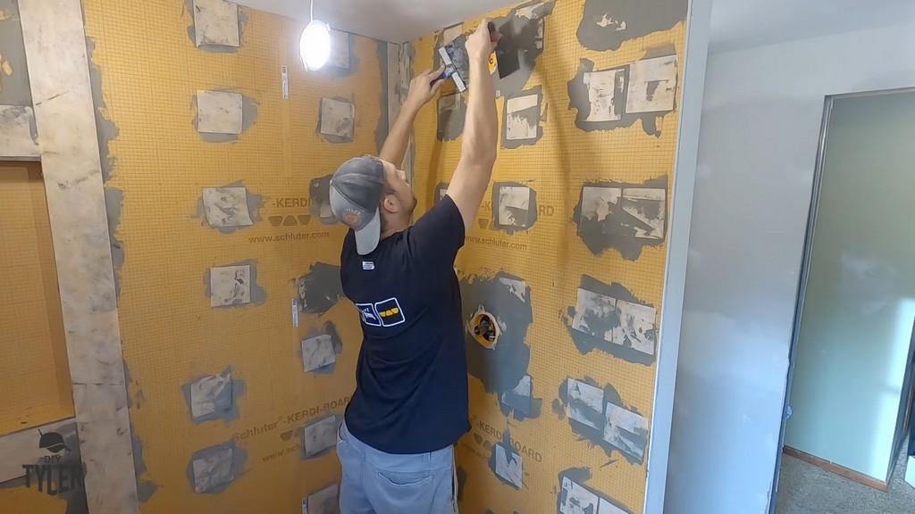 man mudding over seal piece for waterproofing walk-in shower