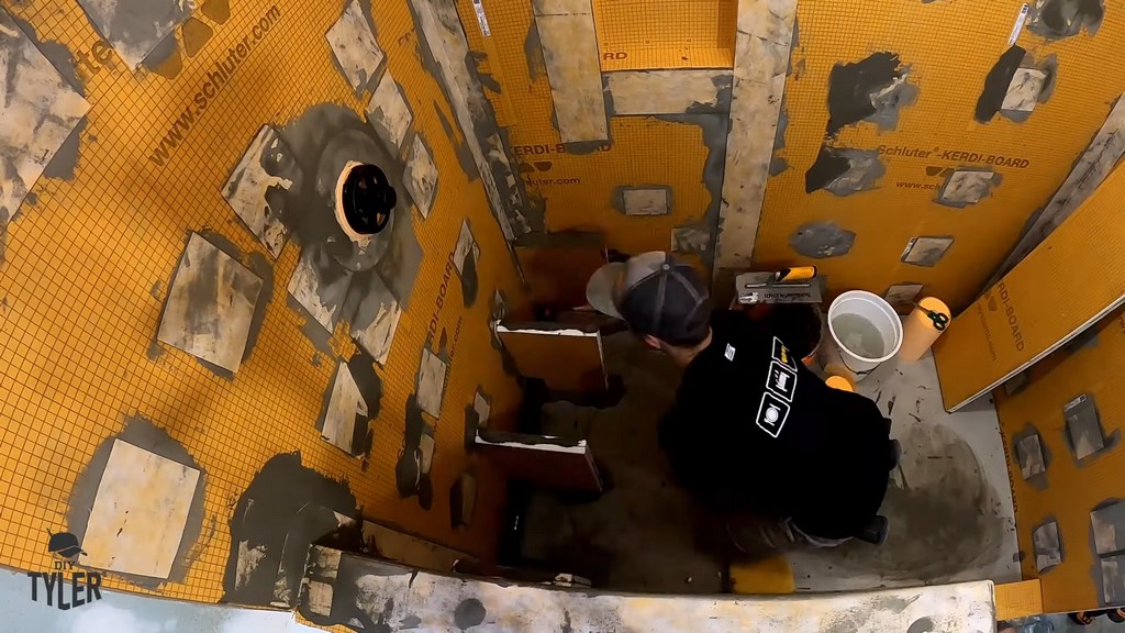 man installing leg pieces for bench inside of incomplete walk-in shower