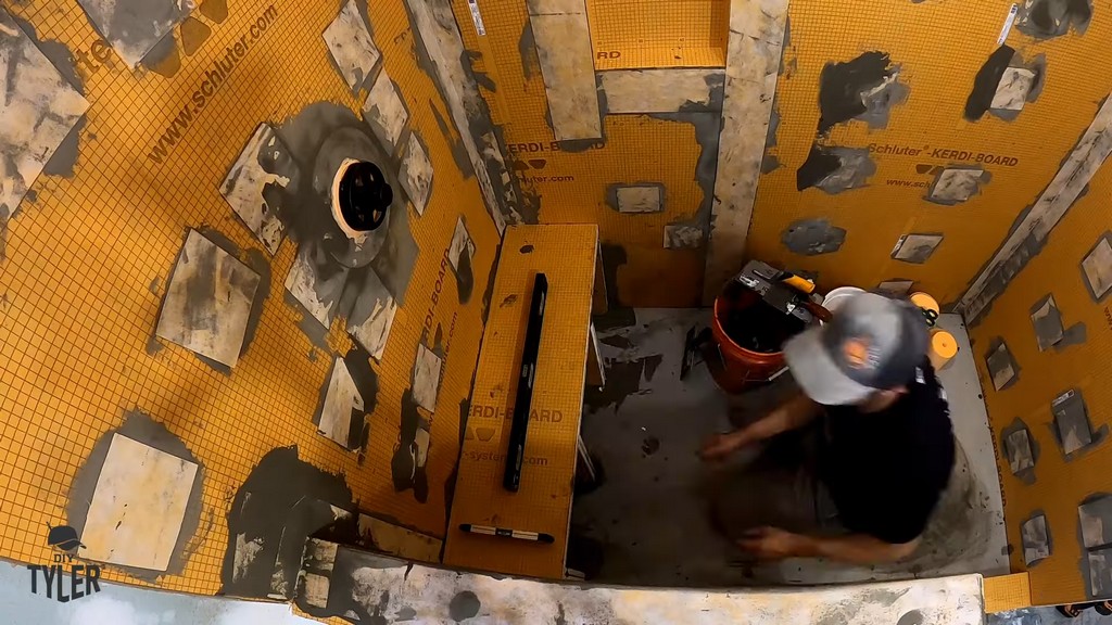 man installing wall pieces to walk-in shower bench