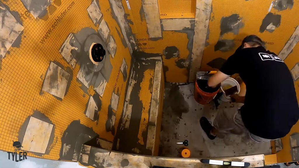 man applying mud and Kerdi band to bench for walk-in shower