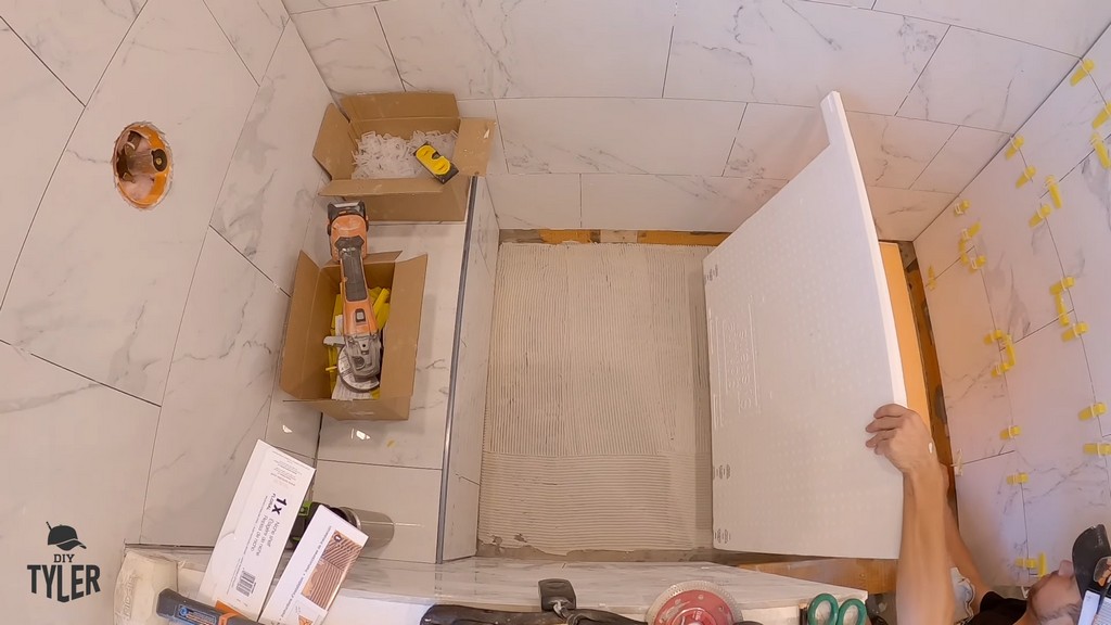 man installing shower pan into unfinished walk-in shower