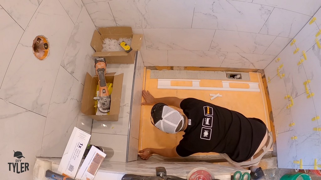 man installing shower pan into unfinished walk-in shower