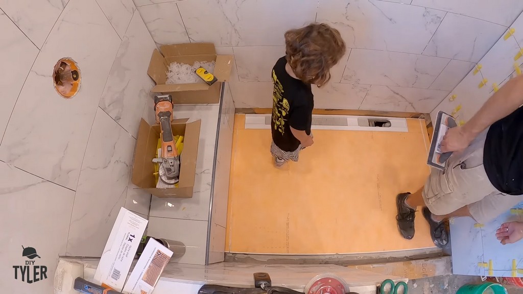 man and child tamping down shower pan for walk-in shower