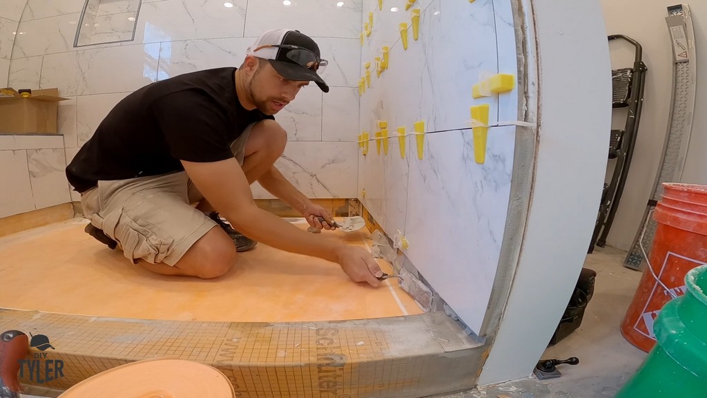 man applying mud to floor seams of walk-in shower