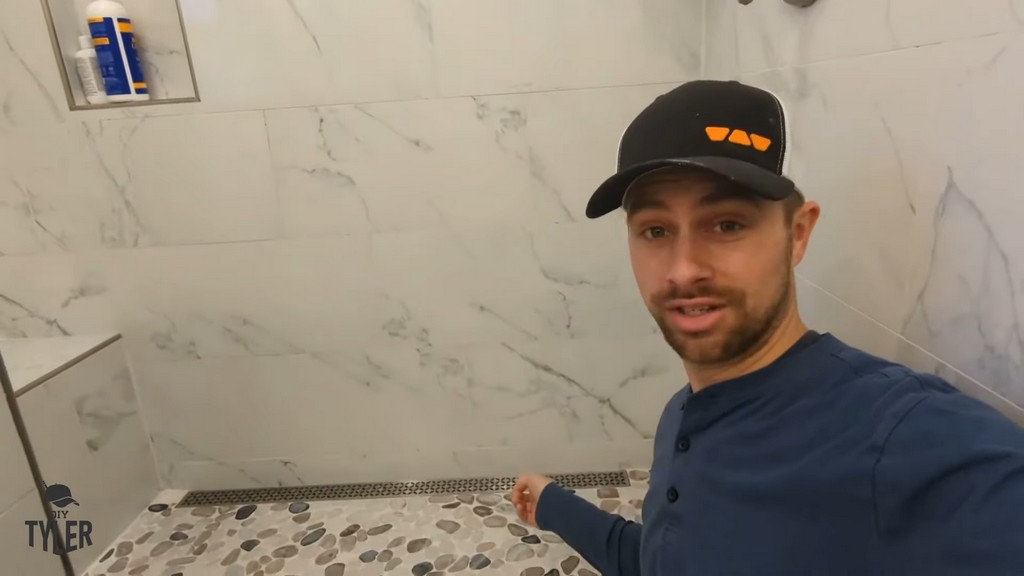 man standing in front of completed walk-in shower including floor drain