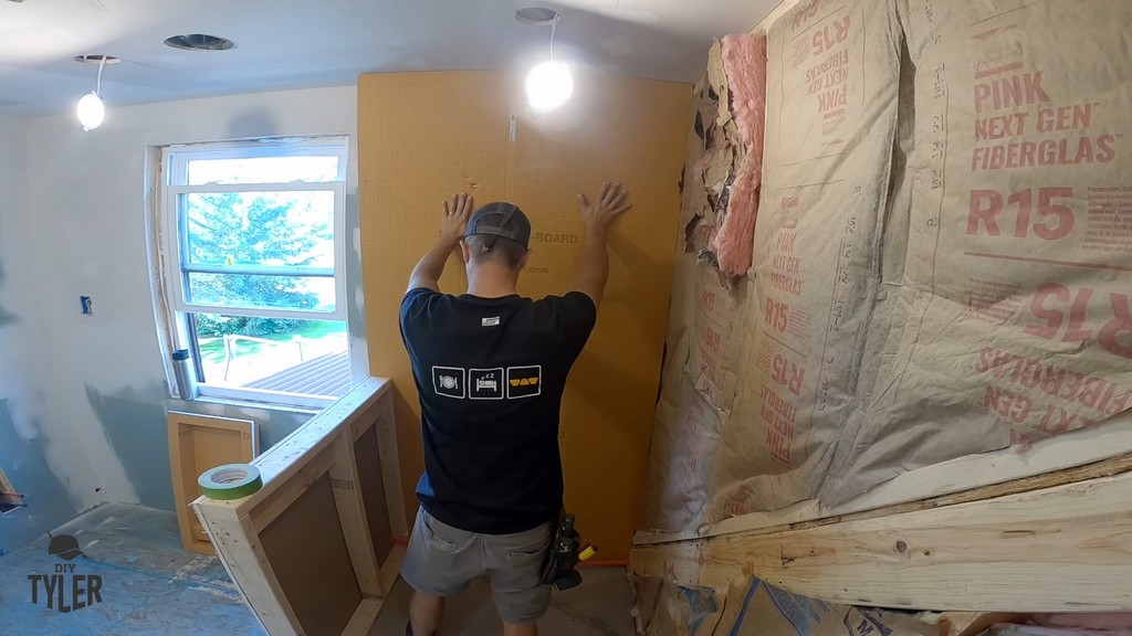 man sliding Kerdi board into place in walk-in shower