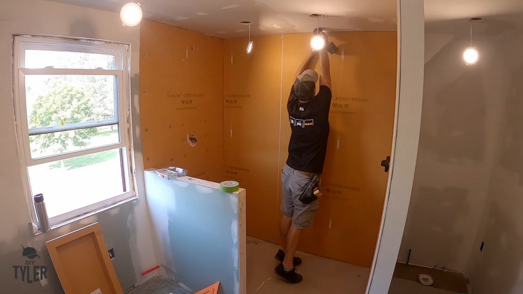 man installing Kerdi board into walk-in shower