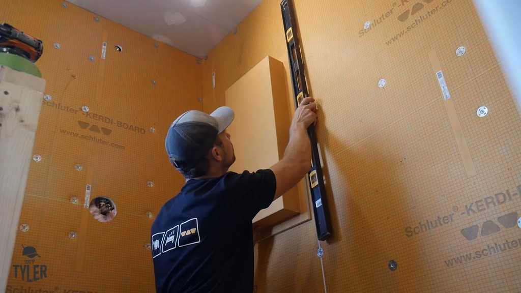 man marking cut lines for walk-in shower niche