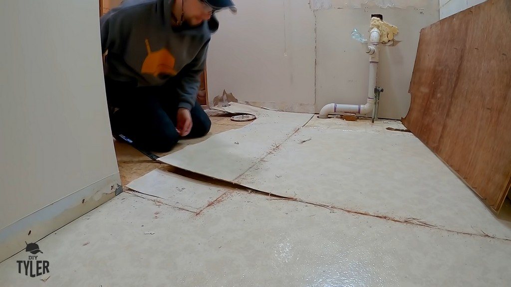 man tearing up one-sheet linoleum flooring with crowbar