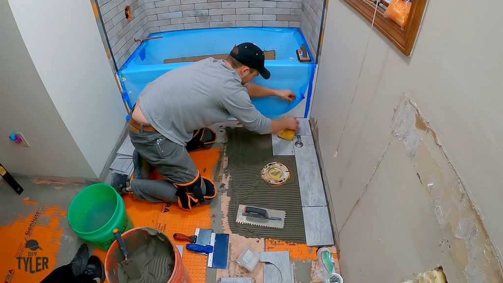 man wiping off bathroom tiles with wet sponge