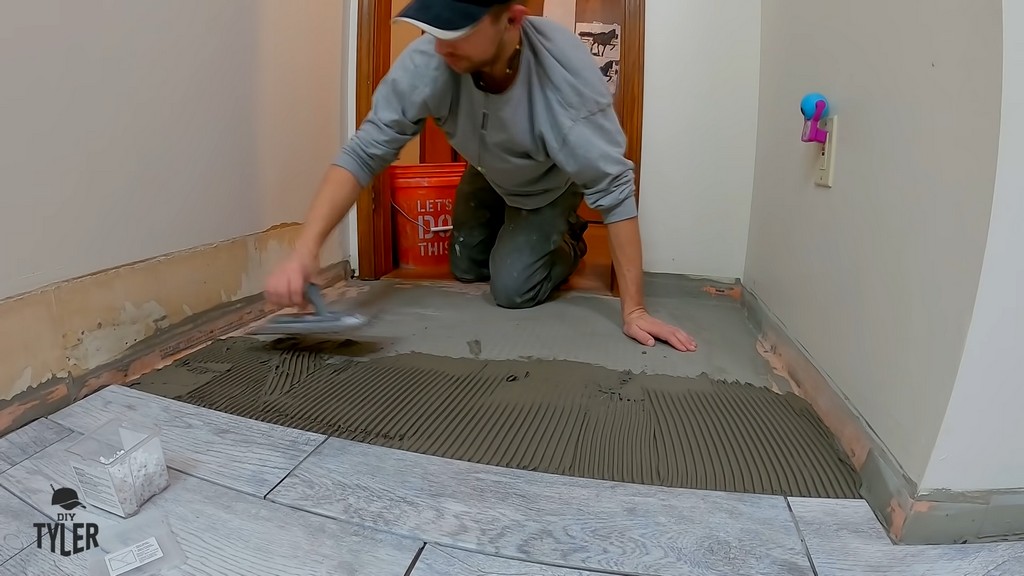 man spreading out mortar on bathroom flooring for DIY tiling