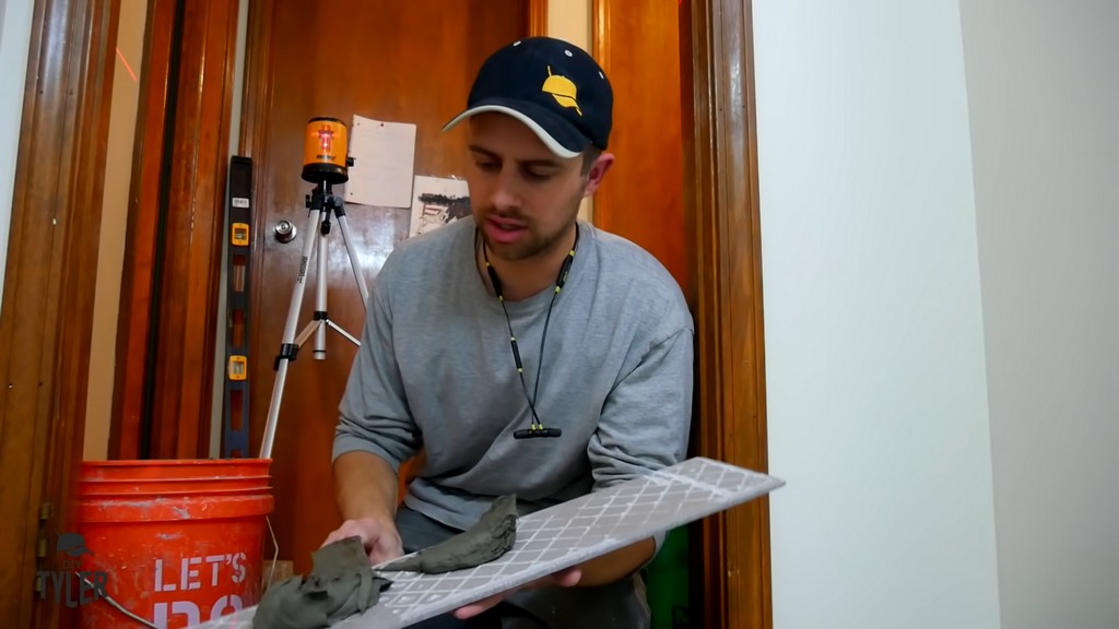 man demonstrating back butter technique for DIY tiling