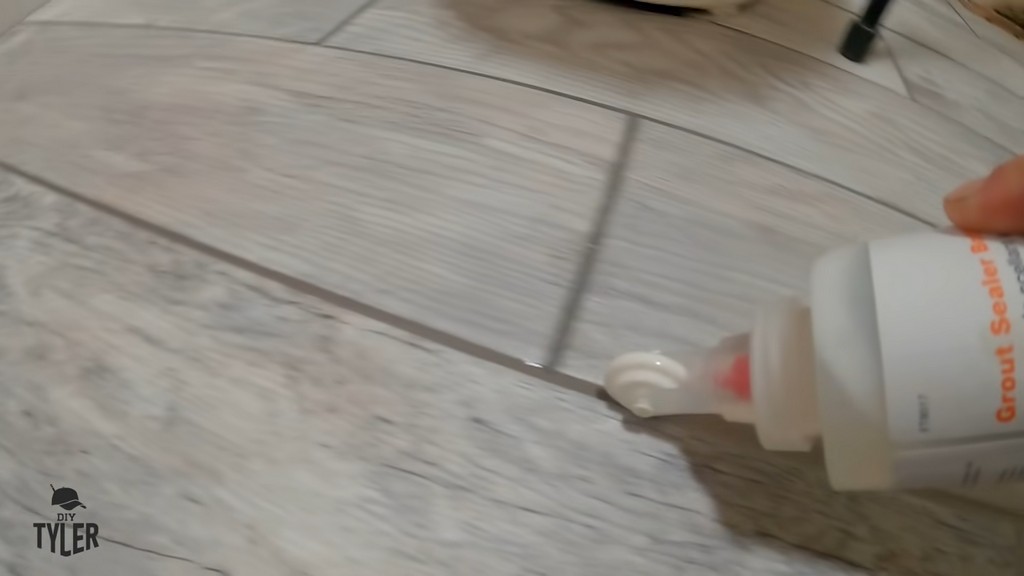 man applying grout sealer to bathroom tile grout lines