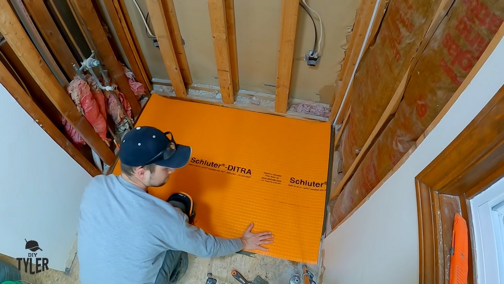 man installing underlayment to bathroom