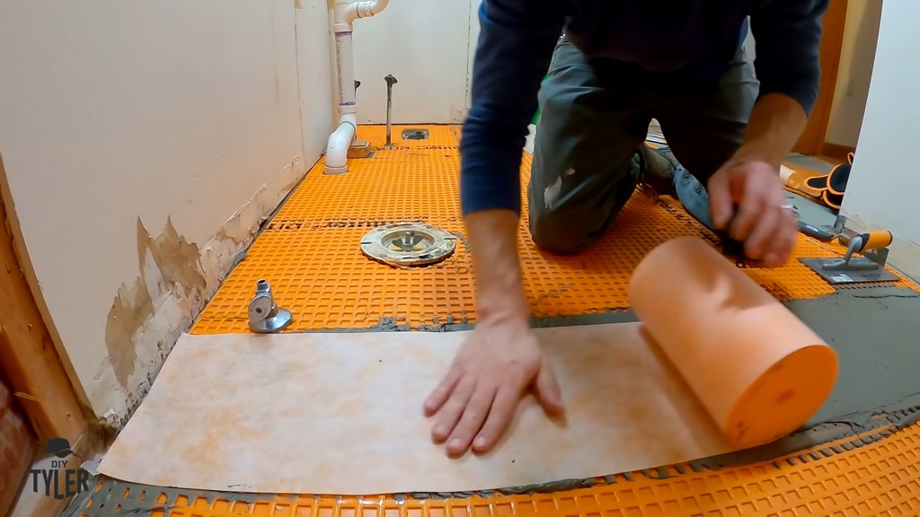 man applying KERDI wrap to seam of Schluter DITRA underlayment