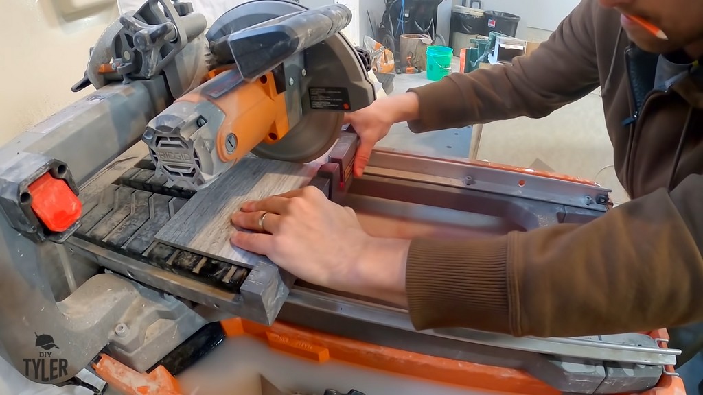 man cutting into bathroom tile with saw