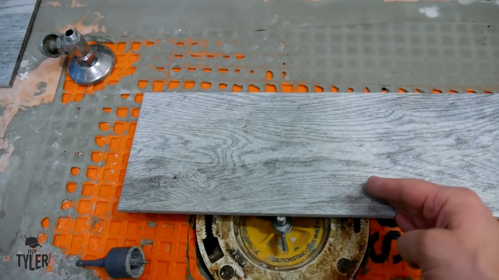 man demonstrating toilet flange and bathroom tile