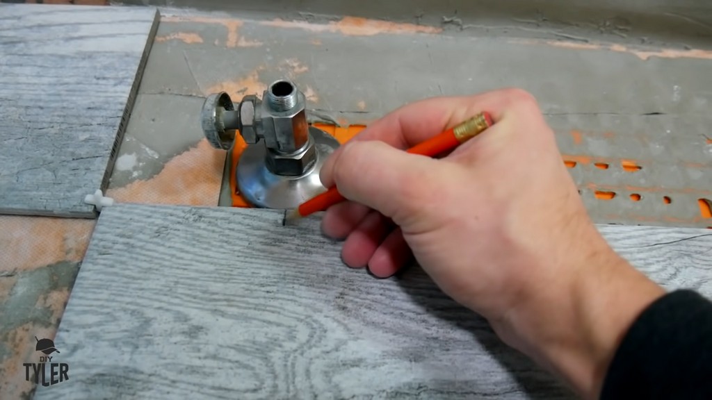 man making mark for hole in bathroom tile