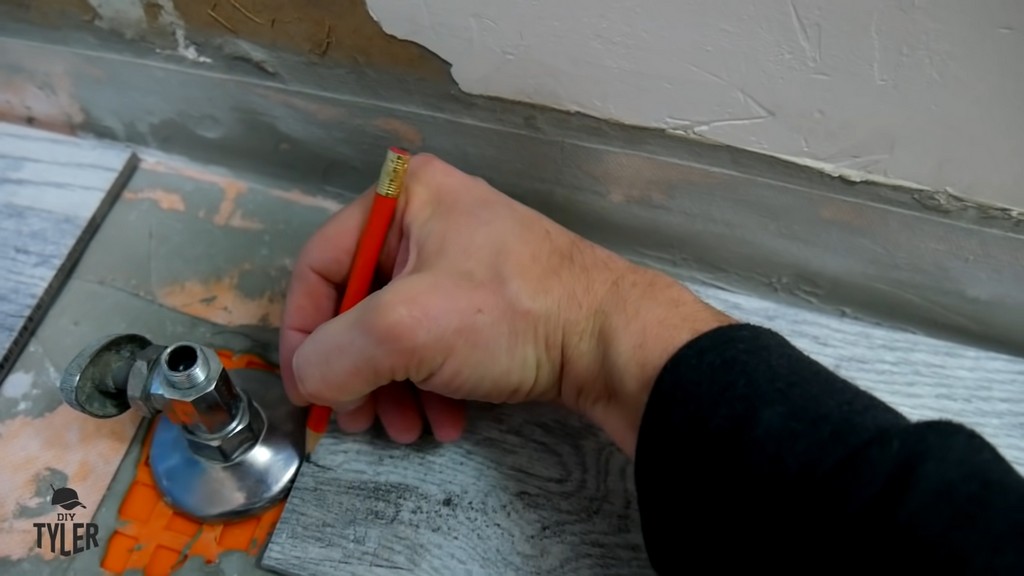 man making mark for hole in bathroom tile