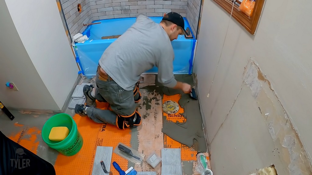 man applying mortar to flooring for tiling