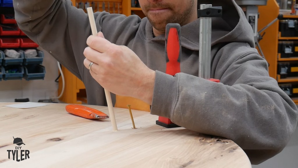 man inserting dowel into DIY round coffee table