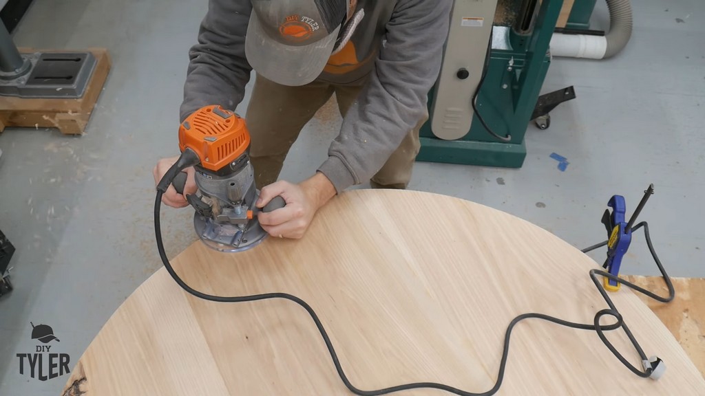 man cutting edge of round hickory tabletop using flush trim router bit