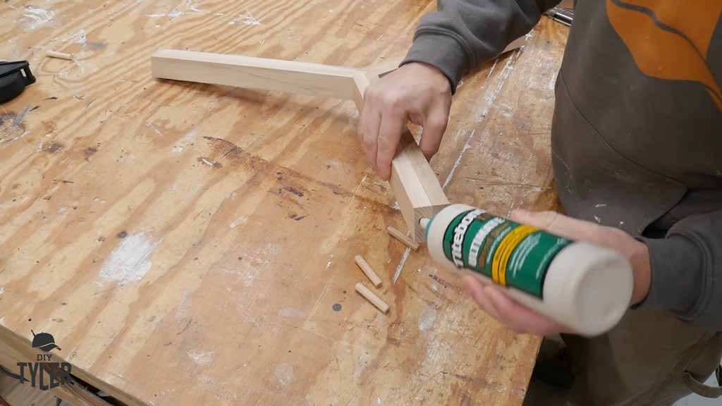 man inserting wood glue into dowel hole for tripod joint brace