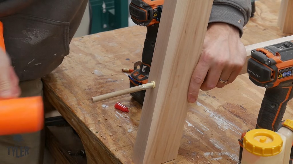 man using mallet to insert dowel into angled table leg for DIY round coffee table