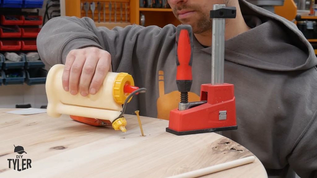 man applying wood glue to dowel hole for DIY round coffee table