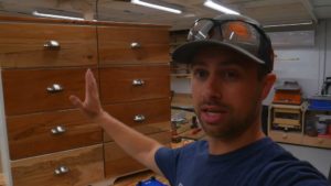 man demonstrating completed installation of cherrywood drawer fronts on dresser