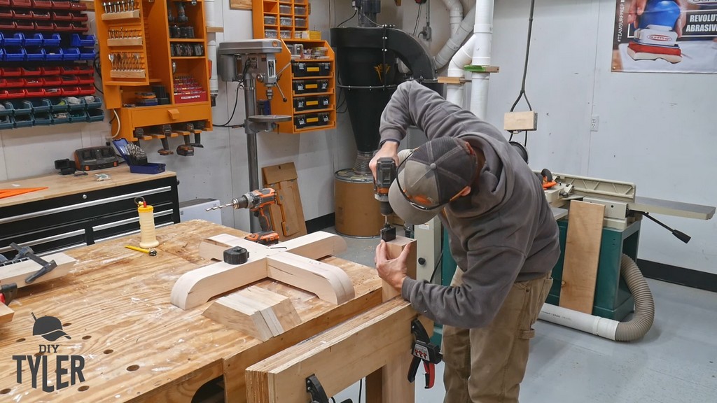 man drilling dowel holes into pedestal game table piece