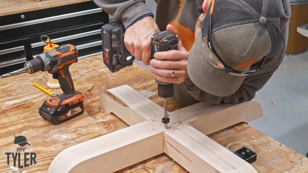 man drilling dowel hole into pedestal game table base piece