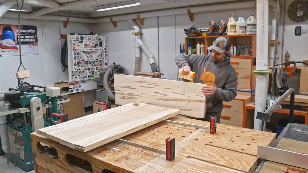 man applying glue to maple wood slabs for tabletop