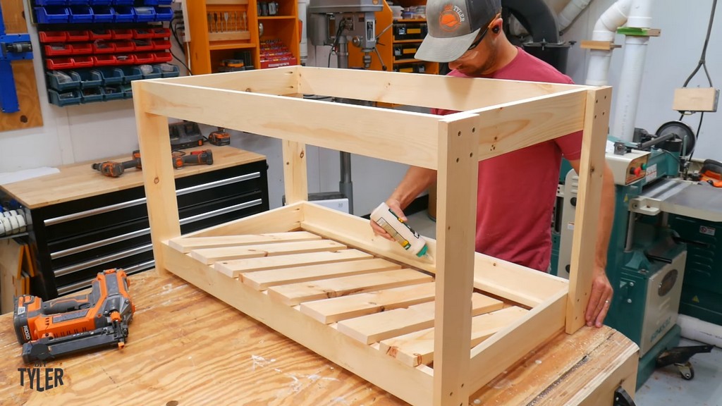 man applying glue to DIY deck fire table frame for bottom slats