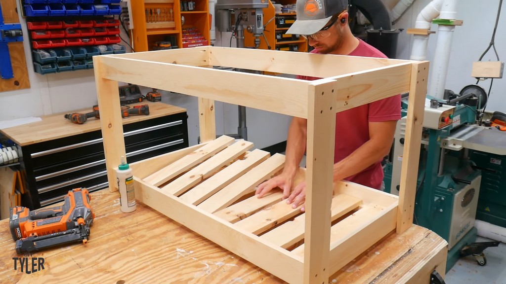 man installing bottom slats for DIY deck fire table frame