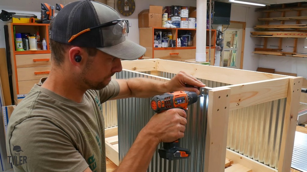 man fastening galvanized paneling into place for DIY deck fire table frame