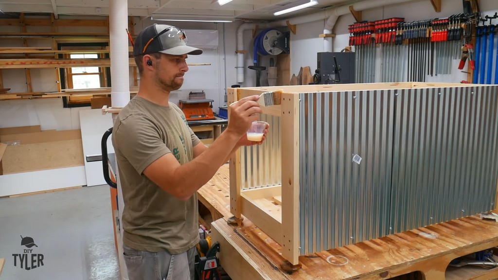 man applying Halcyon brand finish to pinewood frame for DIY deck fire table