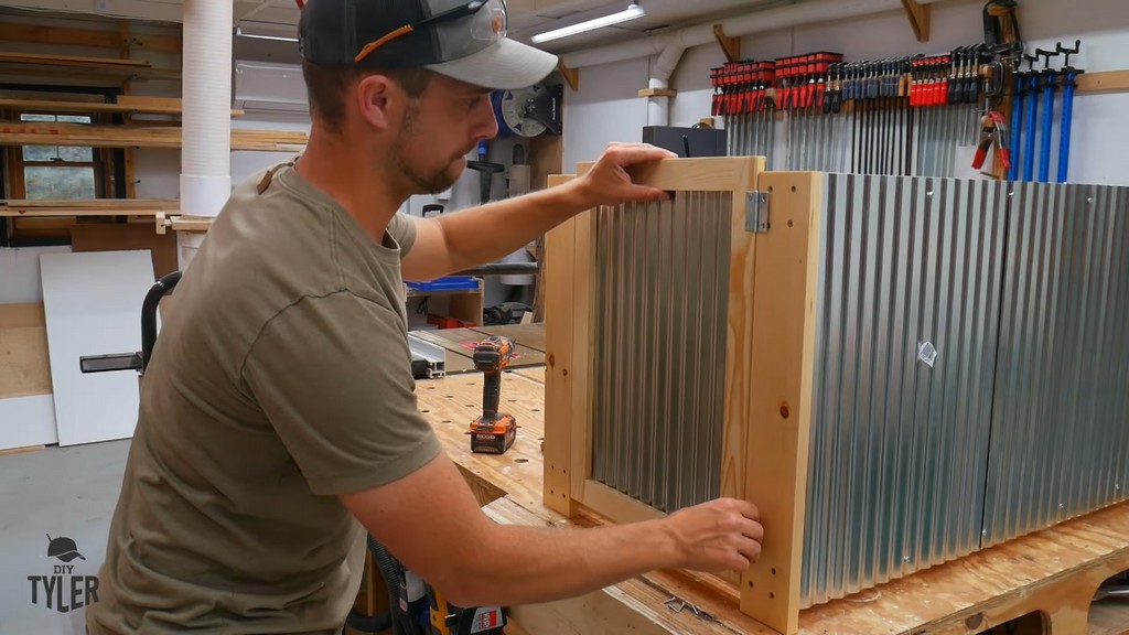 man installing door to side of DIY deck fire table frame