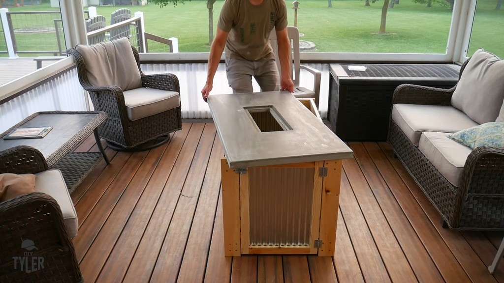 man installing concrete slab onto DIY deck fire table frame on patio