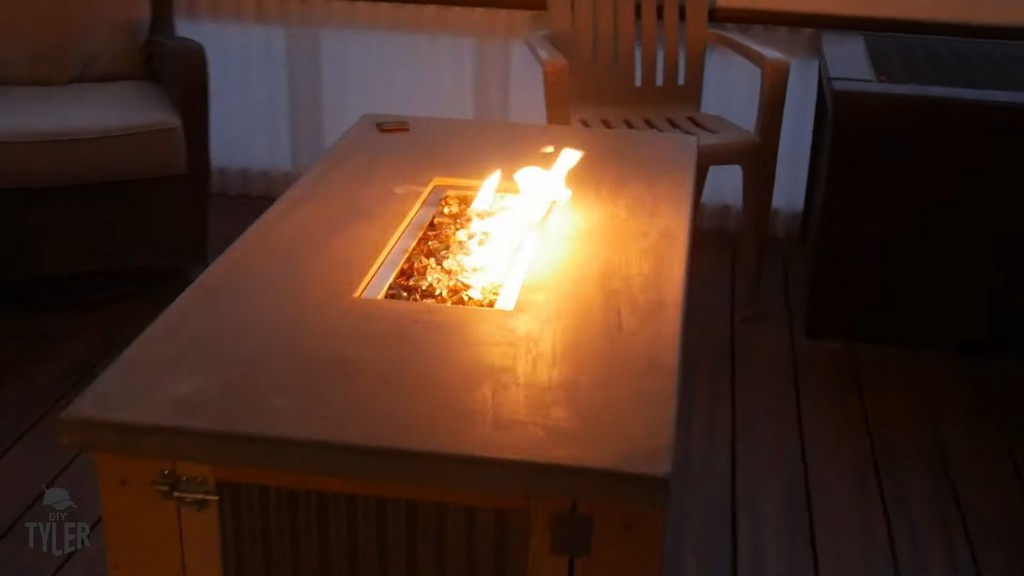 completed DIY deck fire table with lit fire on back patio