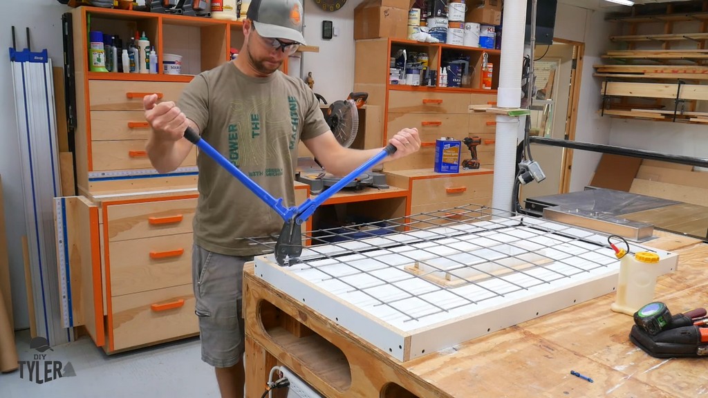 man cutting galvanized metal fencing with bolt cutters