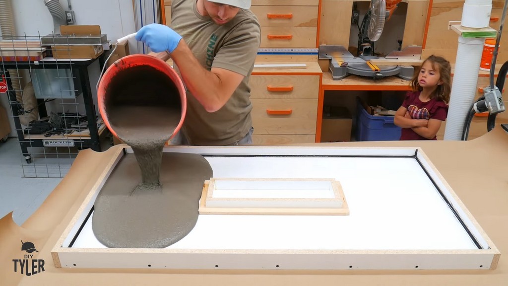 man pouring concrete mix into tabletop mold